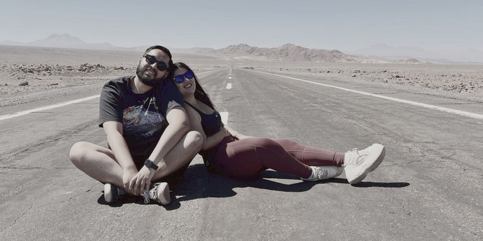Pía y José Luis sentados en medio de una carretera del desierto